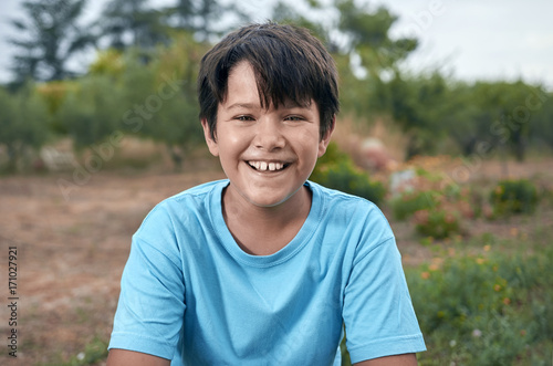 Boy with dark hair in summer outdoors. Smiling