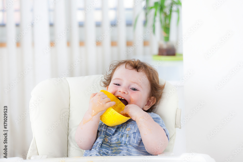 Cute baby boy eating by himself on high chair Cute baby boy eating by himself on high chair
