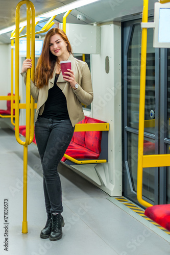 The girl with mug of coffee inside an empty subway train