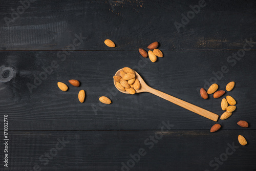 Almonds in spoon on wooden table. Almond nuts.