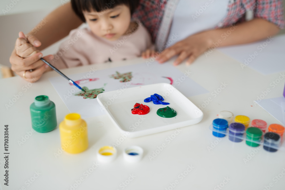 A happy family is painting. Mom help her daughter drawing A happy family is painting. Mom help her daughter drawing