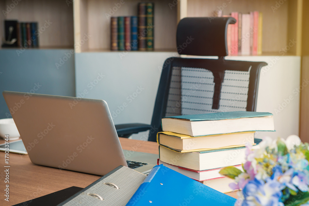 Book stack and laptop on table in office Book stack and laptop on table in office