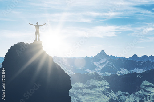 Mountaineer on pinnacle embraces morning sun light