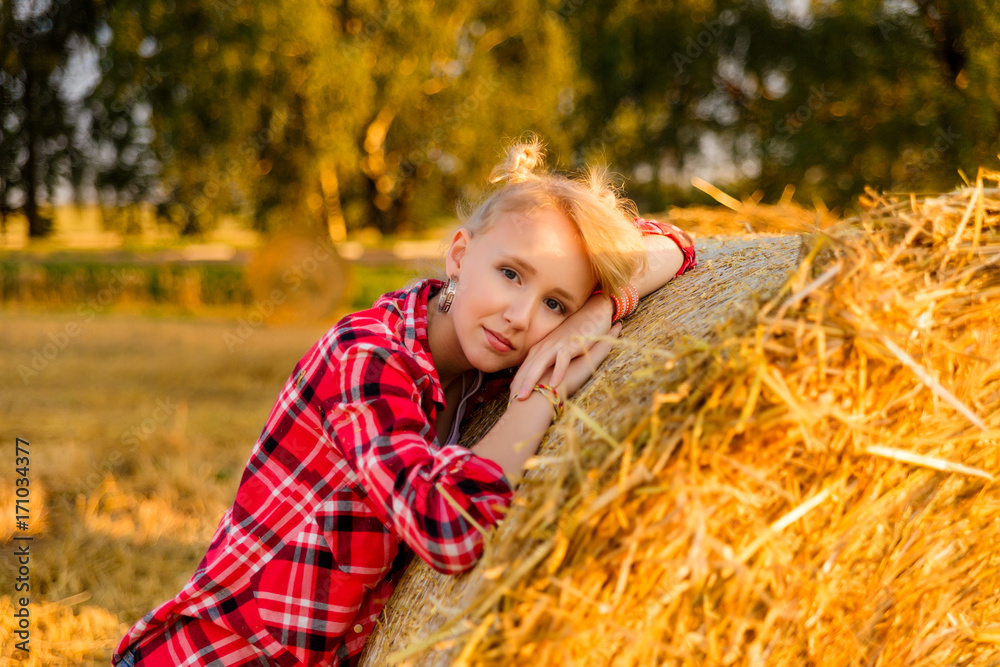 Young girl on straw sheaves in a field Young girl on straw sheaves in a field