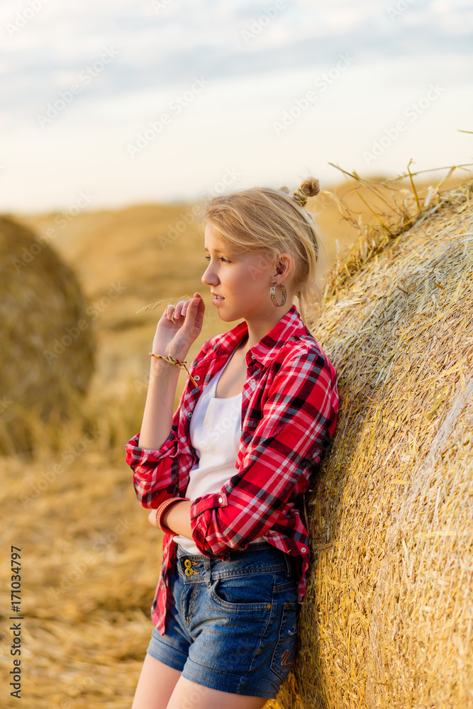 Young girl on straw sheaves in a field Young girl on straw sheaves in a field