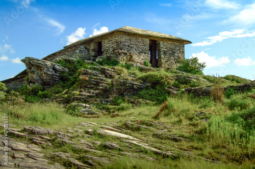 Solitary hut in the woods. Stone cabin on the top of a mountain. Blue sky background