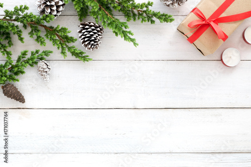 Christmas background. Christmas frame made of fir leaves, pine cones, gift box, candle decoration rustic elements on white wooden. Creative flat lay, top view design