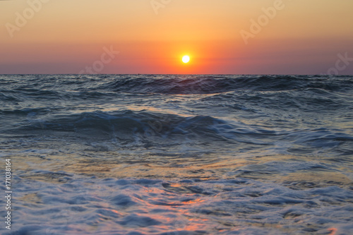 Il sole che tramonta nel mare    sempre una bella chiusura per una giornata di vacanza. Le tonalit   calde donate dal sole si scontrano con il blu delle acque agitate del mare.