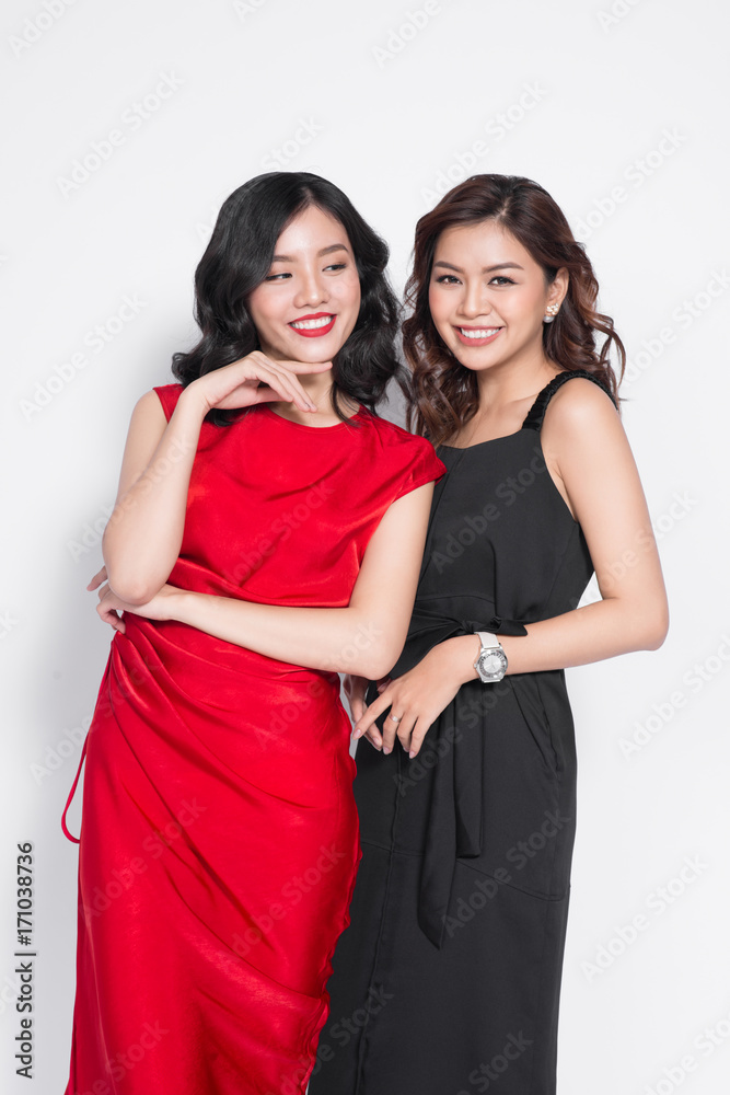 Two fashionable women in nice dresses standing together and having fun Two fashionable women in nice dresses standing together and having fun