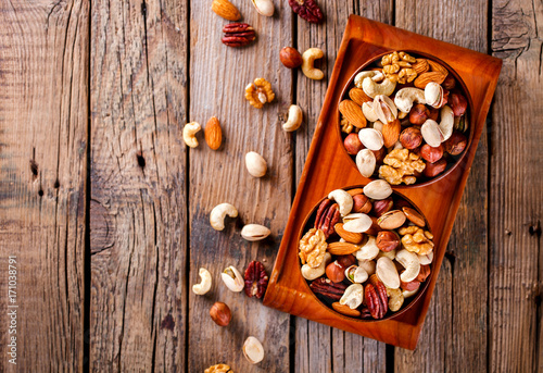 Nuts Mixed in a wooden plate.Assortment, Walnuts,Pecan,Almonds,Hazelnuts,Cashews,Pistachios.Concept of Healthy Eating.Vegetarian.Copy space.selective focus.