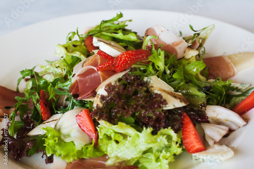 Salad lettuce with parma ham, blue cheese and strawberry serving in restaurant. Gourmet cuisine, close up picture