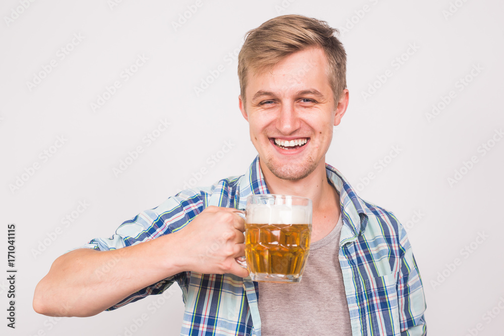 Cheerful young man holding a beer mug full of beer and smiling on white background Cheerful young man holding a beer mug full of beer and smiling on white background