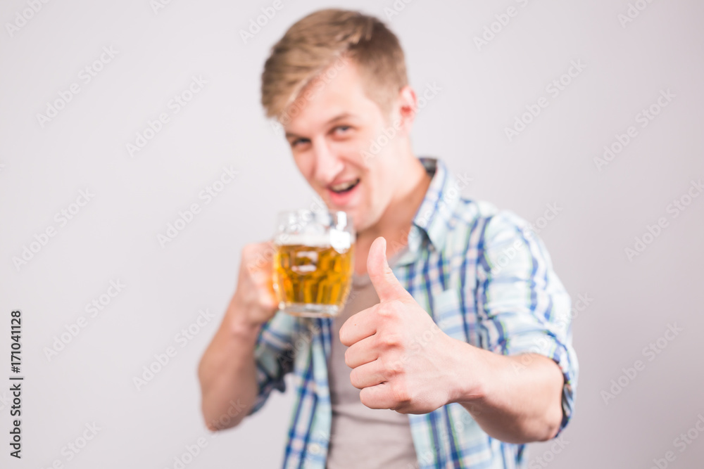 Happy young man holding beer mug and showing thumbs up Happy young man holding beer mug and showing thumbs up