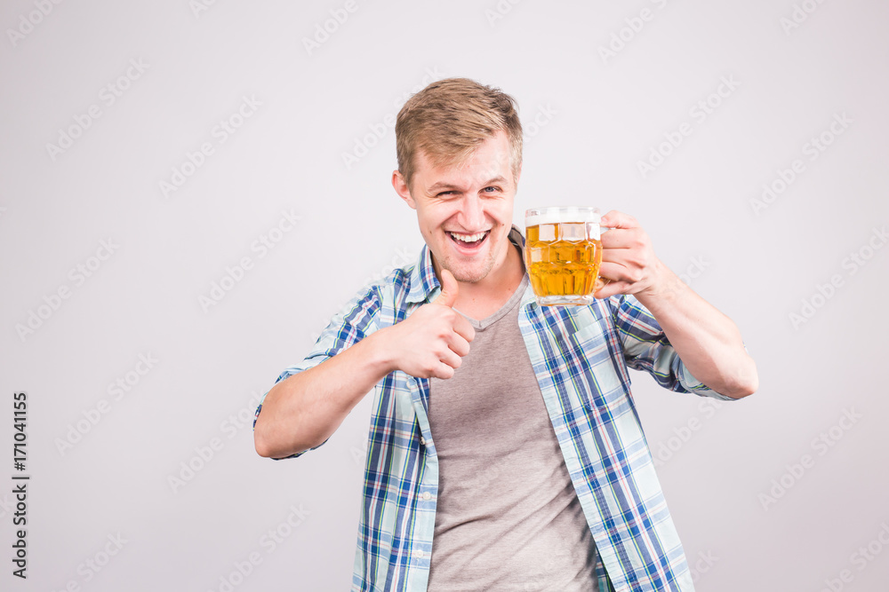Happy young man holding and pointing on a beer mug Happy young man holding and pointing on a beer mug
