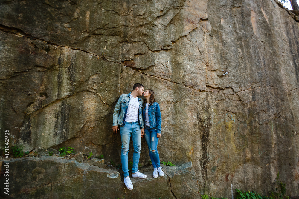 Man and woman standing arm in arm on a rock, sunset