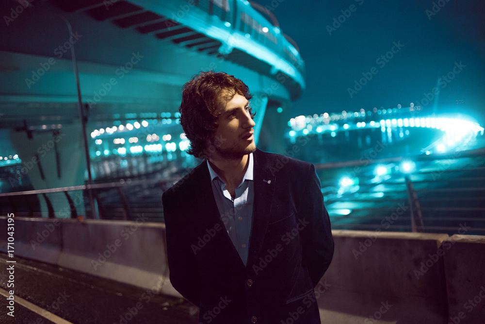 Fototapeta premium Young stylish guy on the background of night city, city lights