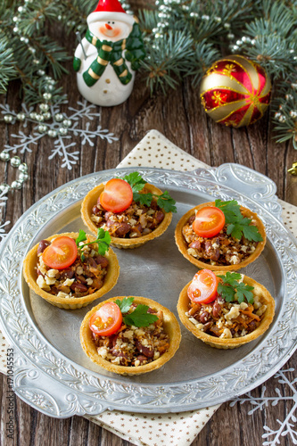 Tartlets with beans, meat and walnuts. Beautiful Christmas and New Year's food background. Selective focus.