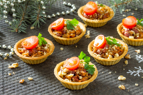 Tartlets with beans, meat and walnuts. Beautiful Christmas and New Year's food background. Selective focus.