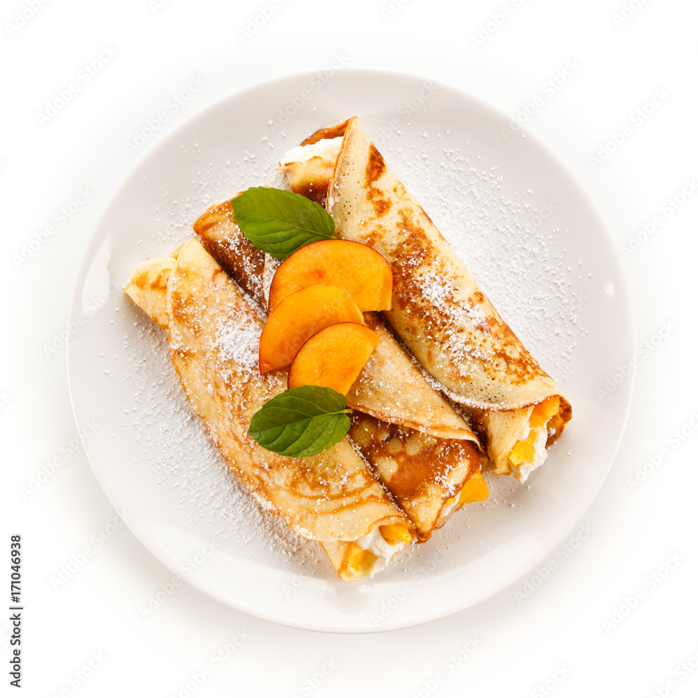 Crepes with peaches and cream on white background Crepes with peaches and cream on white background