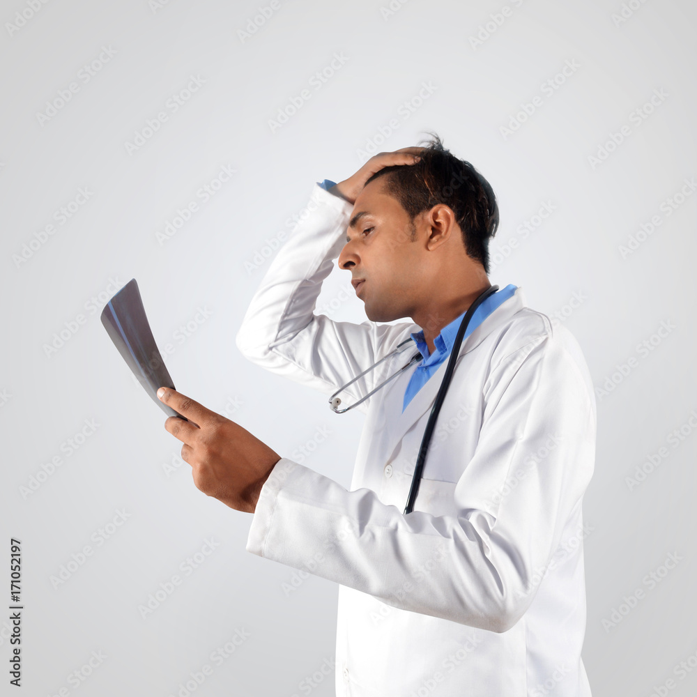Shocked doctor with stethoscope examining x-ray