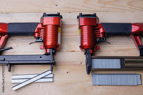 Fényképezés Close up pneumatic nailer gun on wooden background.