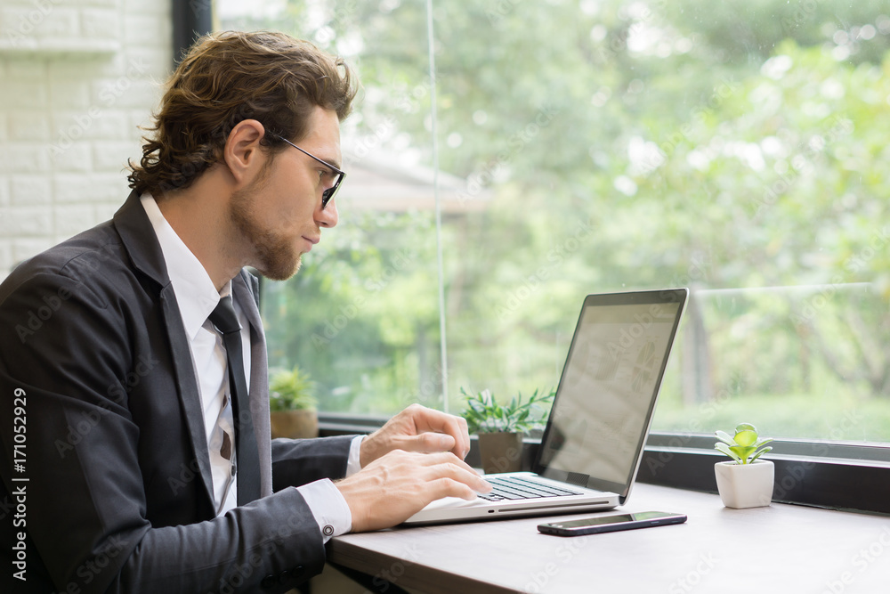 Young businessman working on laptop at office. Working people concept. Young businessman working on laptop at office. Working people concept.