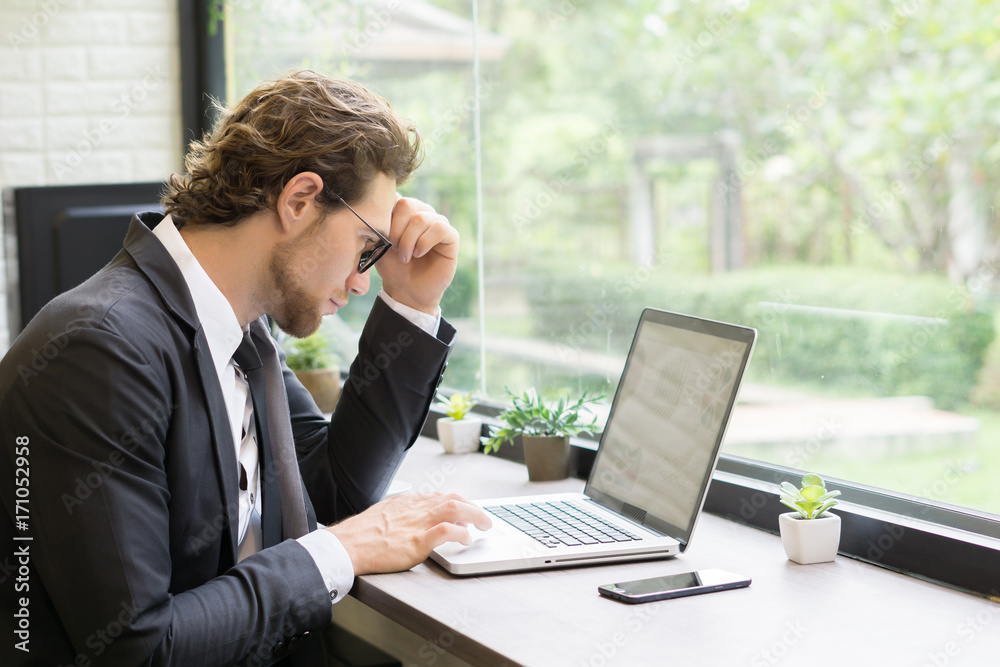 Young businessman working on laptop at office. Working people concept. Young businessman working on laptop at office. Working people concept.
