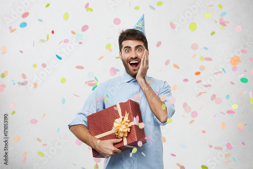 Photography Portrait of excited unshaven birthday guy in formal shirt feeling happy and fasc