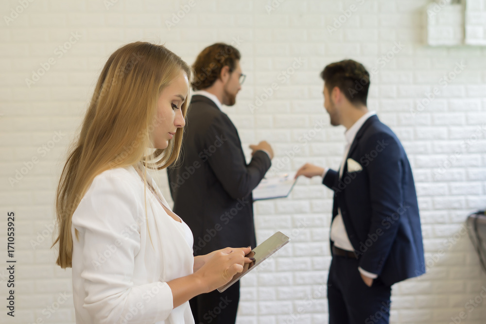 Businesswoman using digital tablet while coworker interacting in the background in the office Businesswoman using digital tablet while coworker interacting in the background in the office