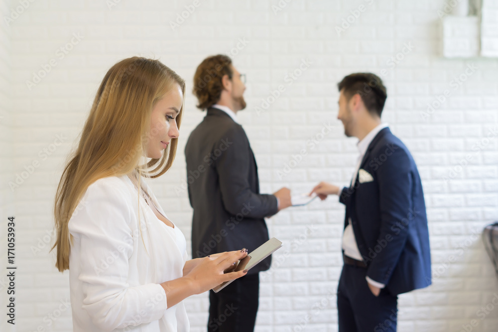 Businesswoman using digital tablet while coworker interacting in the background in the office Businesswoman using digital tablet while coworker interacting in the background in the office