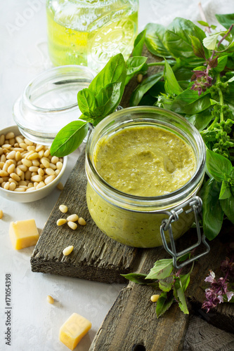 Green pesto sauce, basil, parmesan and pine nuts on a stone or slate table. Healthy Italian cuisine. Copy space.