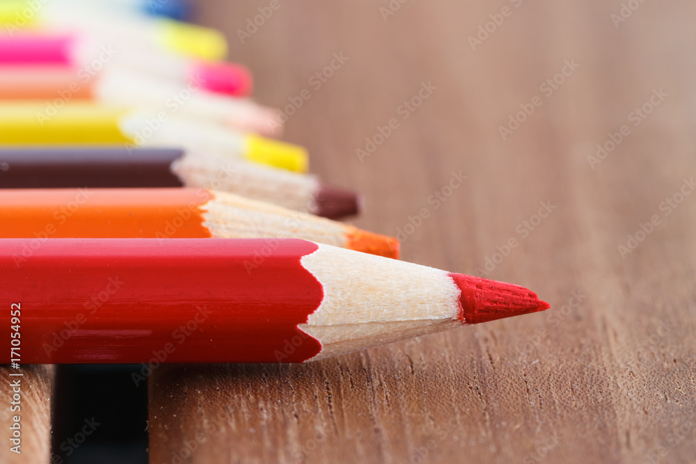 Obraz premium Set of colored pencils with a single sharp one symbolizing leadership concept
