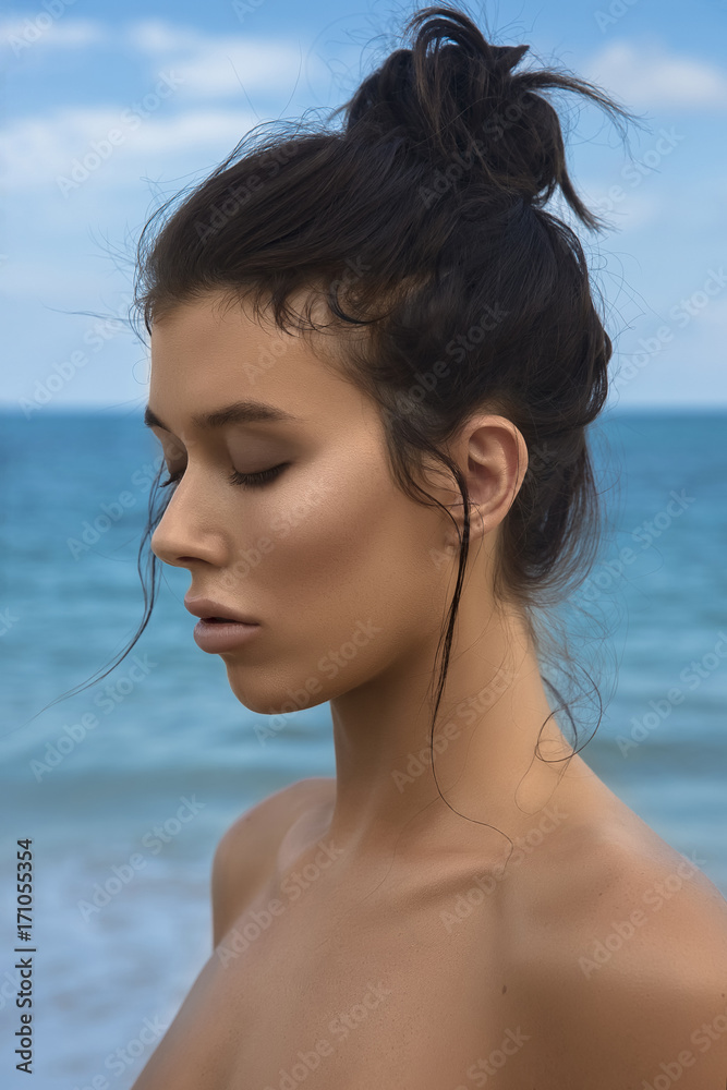 Close-up portrait of a young beautiful well-groomed girl in profile on a blue sky and sea background. Bright lighting - sunlight. Bright colors. Smooth, shiny, well-groomed skin, tan. Advertising. Close-up portrait of a young beautiful well-groomed girl in profile on a blue sky and sea background. Bright lighting - sunlight. Bright colors. Smooth, shiny, well-groomed skin, tan. Advertising.