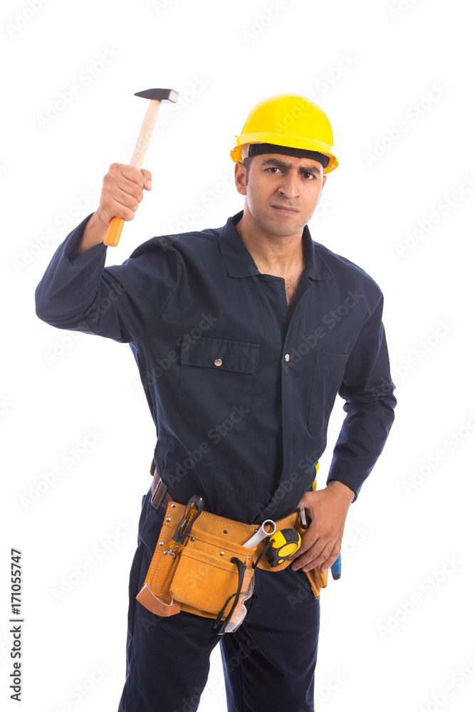 Happy beard worker smiling and hitting with a hammer, guy wearing dark blue workwear and belt equipment with yellow helmet, isolated on white background Happy beard worker smiling and hitting with a hammer, guy wearing dark blue workwear and belt equipment with yellow helmet, isolated on white background