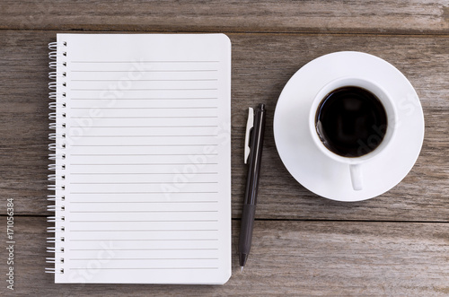 notebook with coffee cup on wooden background.