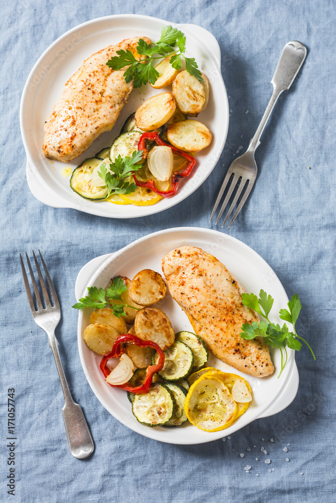 Roasted chicken provencal with zucchini, squash, potatoes. Delicious healthy lunch on a blue background, top view