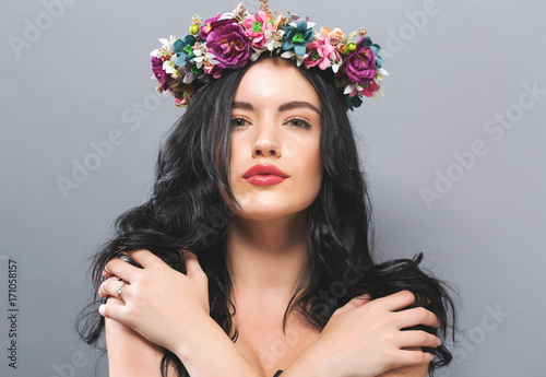 Beautiful young woman with a garland on a solid background