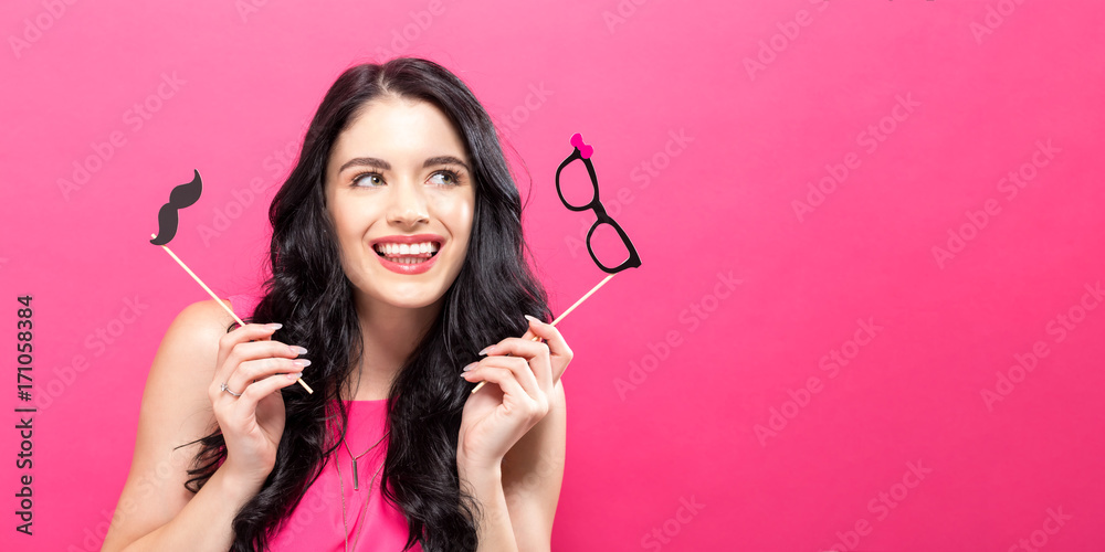 Young woman holding paper party sticks on a solid background Young woman holding paper party sticks on a solid background