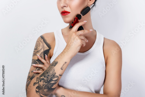 Young woman tattooist with a tattoo-machine in her hand