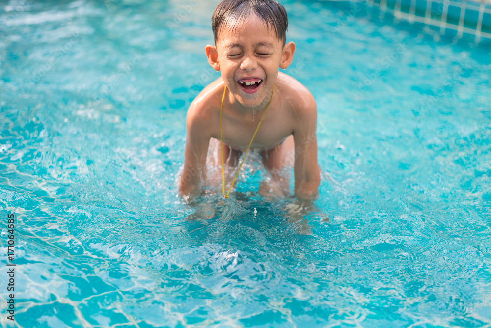 Little asian boy having fun in the pool during summer time.