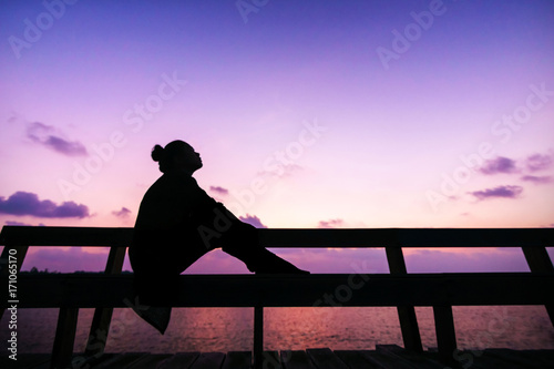 silhouette Women sit on the branch and think about something in her lift with butiful twilight sky photo