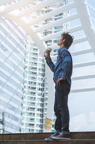 man thinking stand on outdoor floor and holding a cup of coffee at morning ready to working.