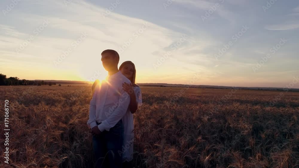 Young beautiful couple in a wheat field. Silhouette on sunset background. Slow motion Young beautiful couple in a wheat field. Silhouette on sunset background. Slow motion