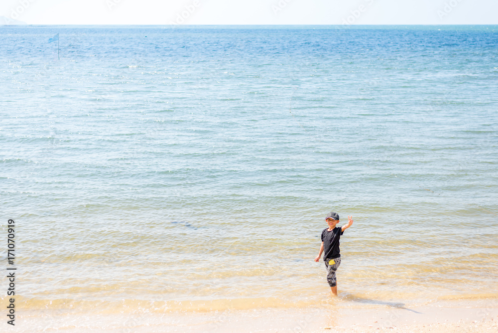 Happy asian boy showing victory sign at the beach Happy asian boy showing victory sign at the beach