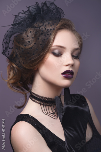 Beauty portrait of a beautiful girl in a gothic image on a purple background.