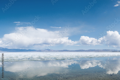 panoramic view of fluffy white clouds reflecting in mirror water of lake 