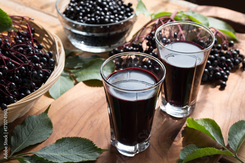 Two glasses of elderberry syrup on a wooden background photo