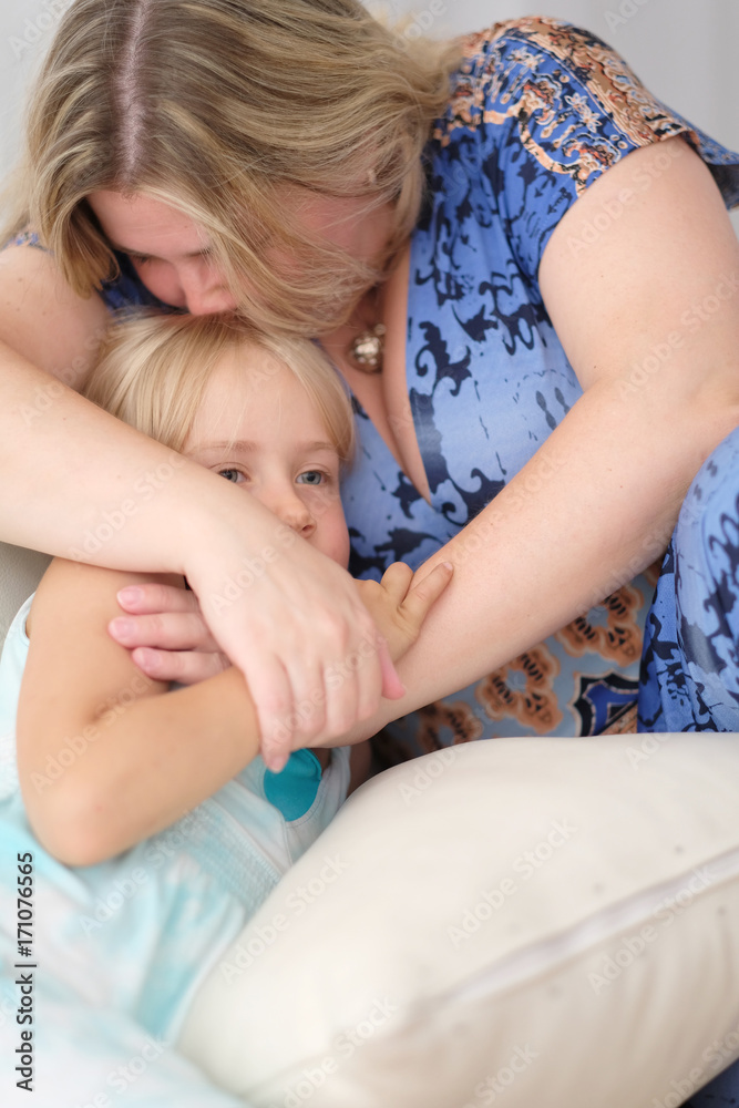 Woman hugging a child sitting on the couch