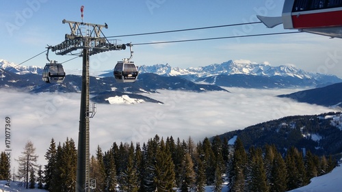 Ski Lift above Clouds between snow-topped mountains 