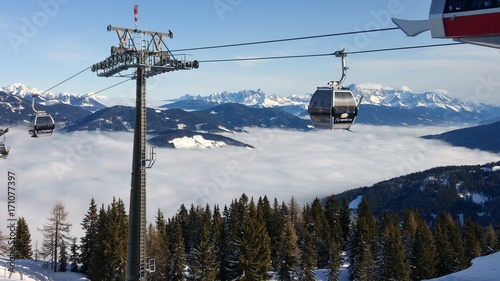 Ski Lift above Clouds between snow-topped mountains 